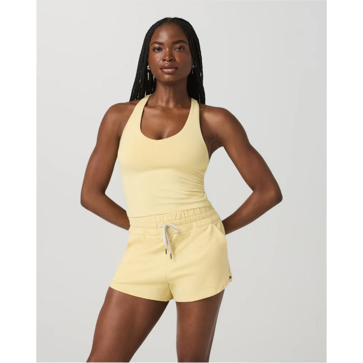Woman wearing a yellow athletic outfit on a light gray background