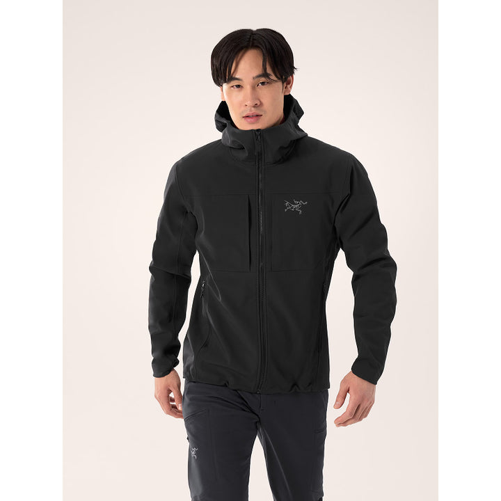 Person wearing a black jacket with a brand logo on a light gray background