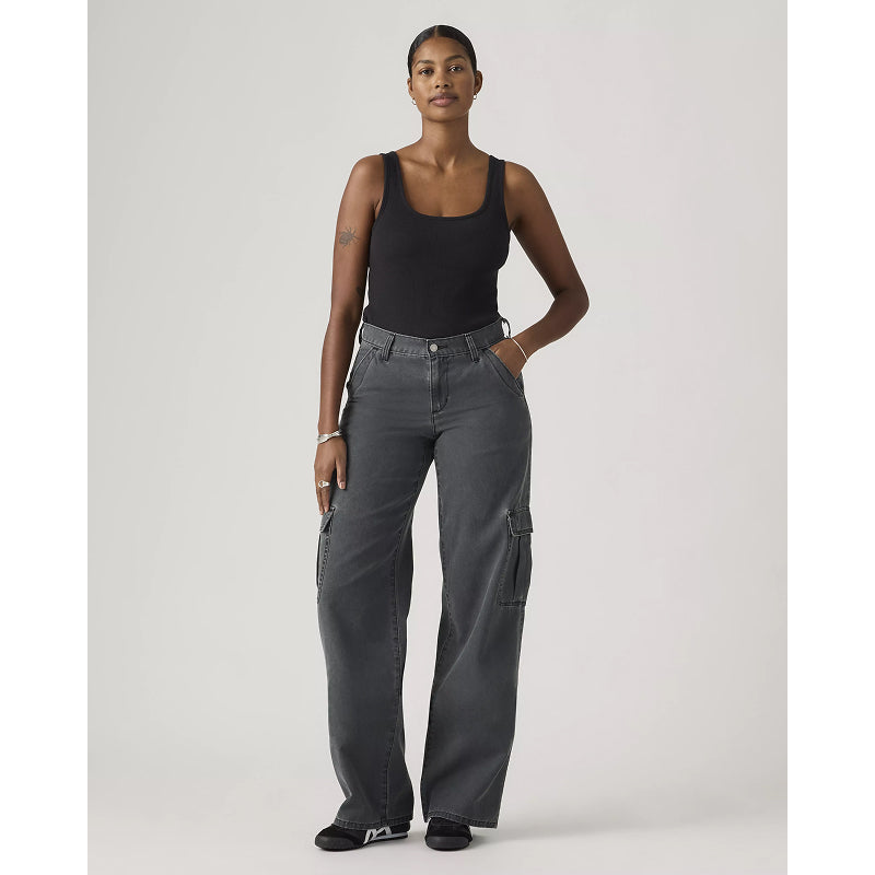 Woman wearing gray cargo pants and a black tank top on a white background