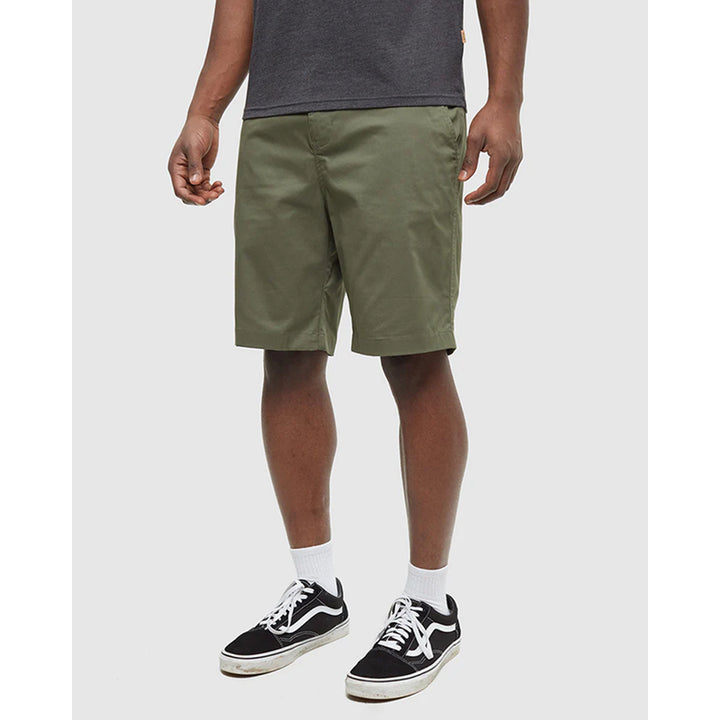 Person wearing green shorts and black sneakers on a white background