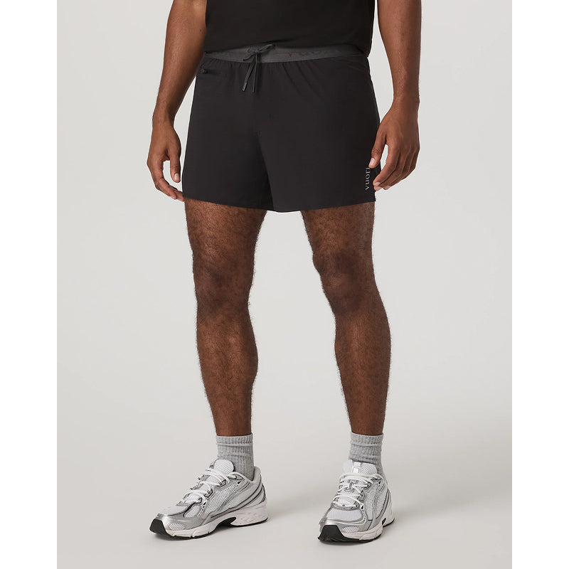 Person wearing black athletic shorts and gray sneakers on a white background