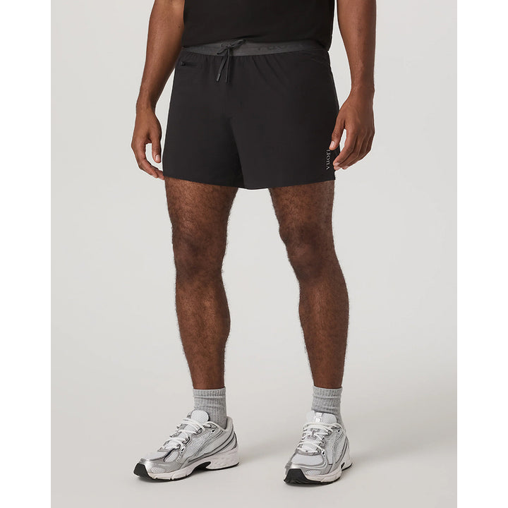 Person wearing black athletic shorts and gray sneakers on a white background